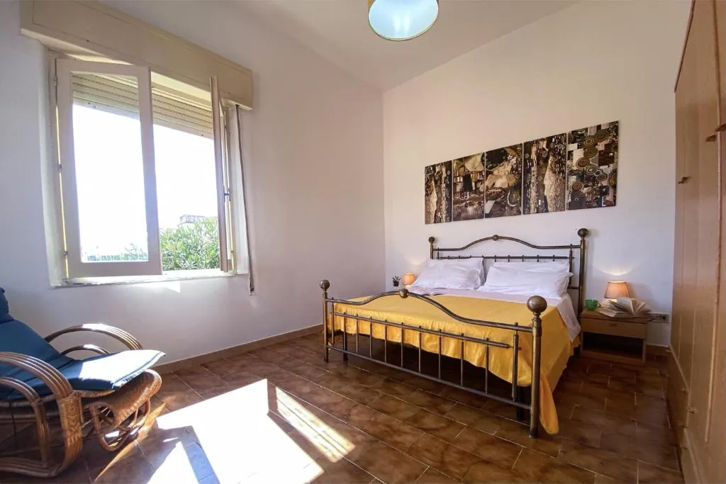 Camera matrimoniale luminosa con letto in ferro battuto e copriletto giallo